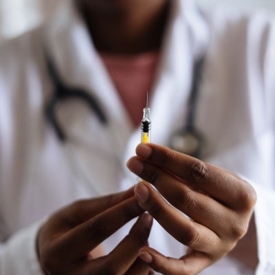 Physician in white coat holding a syringe containing vaccine
